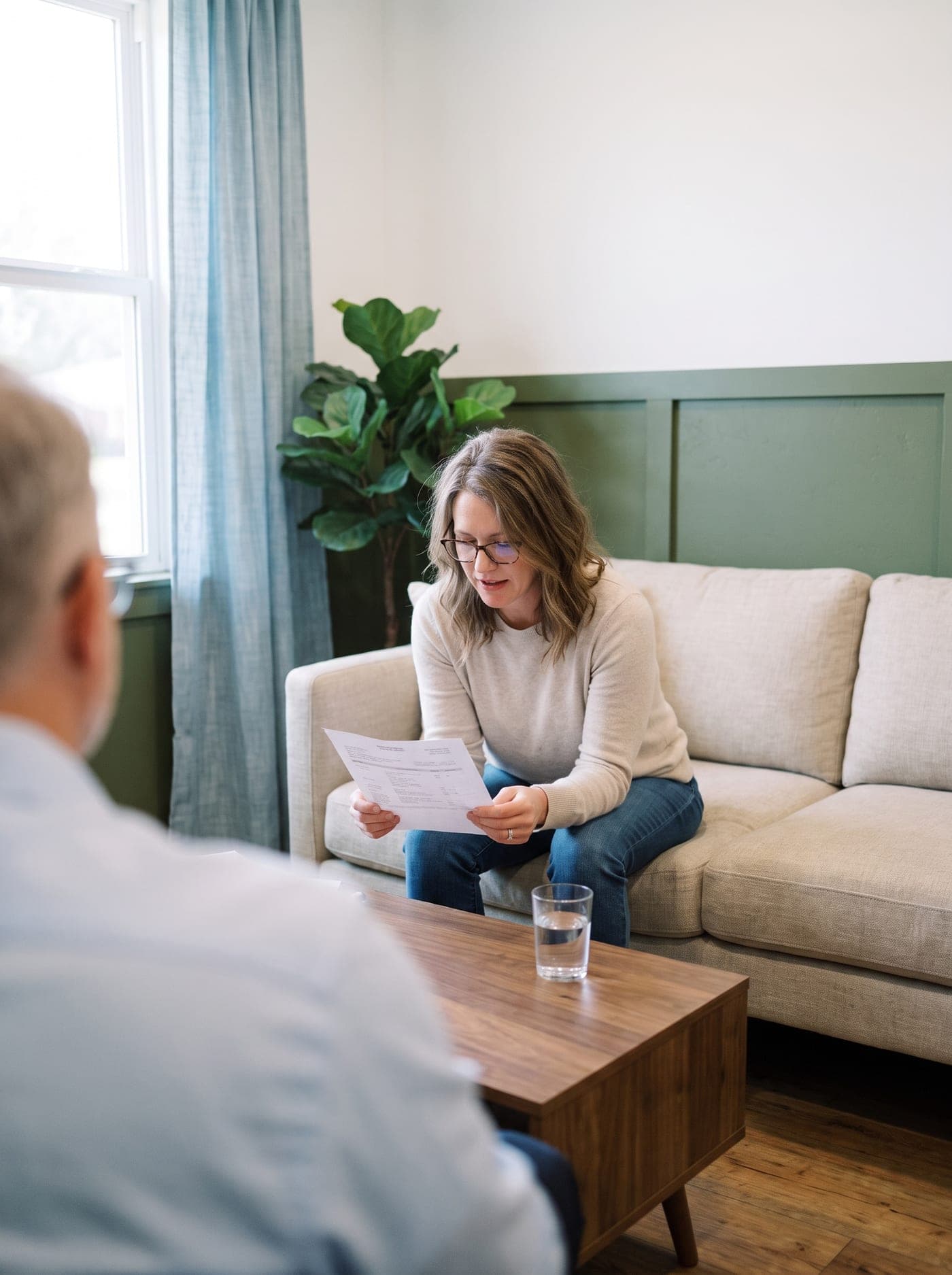 A woman on a sofa reading her lab results, with Dr. Nelson across the coffee table.