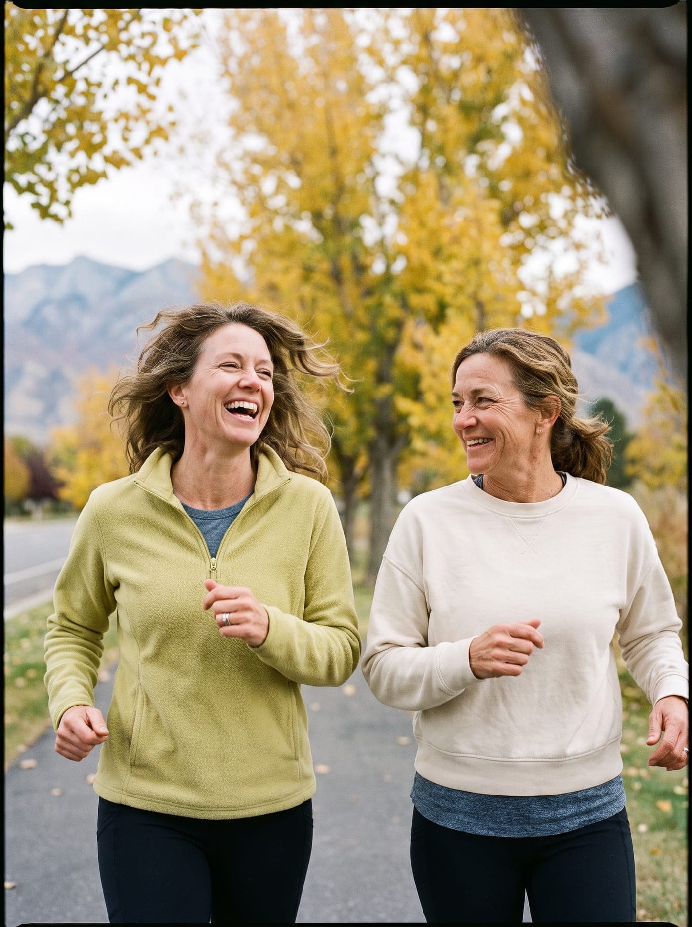 Two friends in their forties laughing together on an autumn walk.